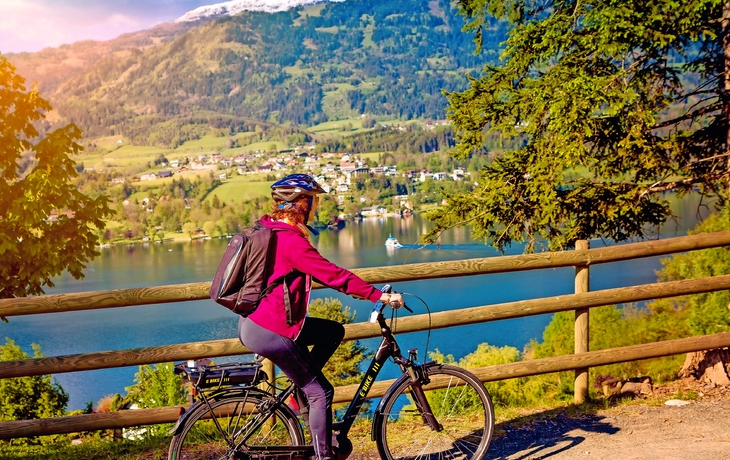 Frau mit E-Bike Radfahren neben einem schönen See-See und Fahrrad